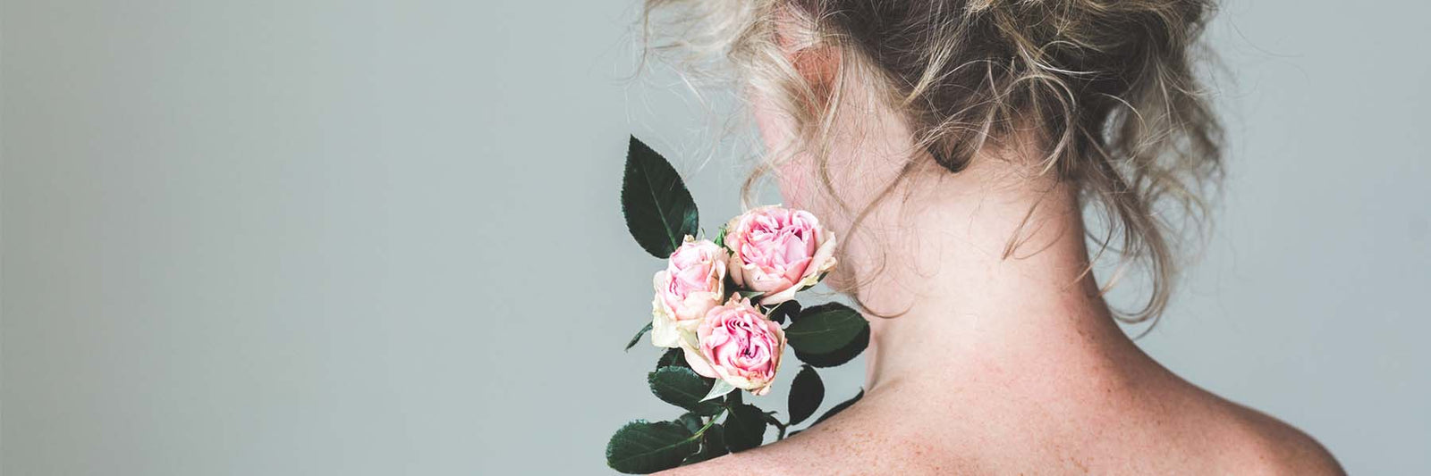 back view of womans neck and holding pink roses
